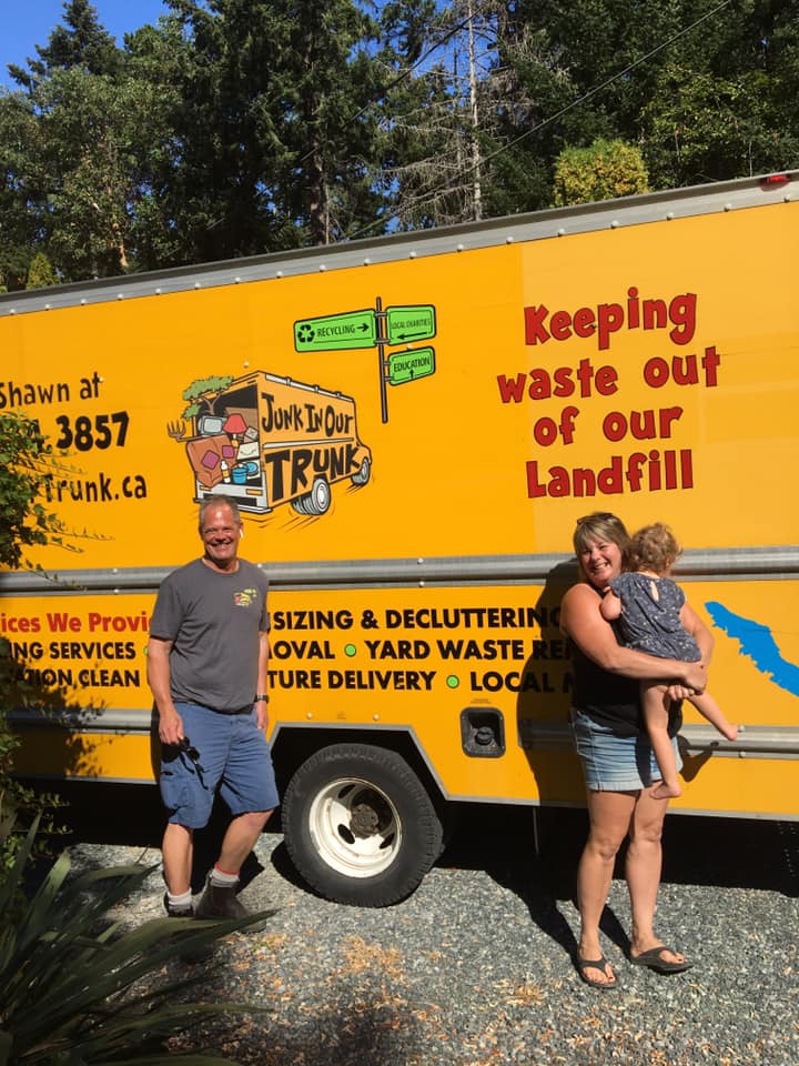 Shawn and a smiling customer holding her child in front of the Junk In Our Trunk truck on a sunny day