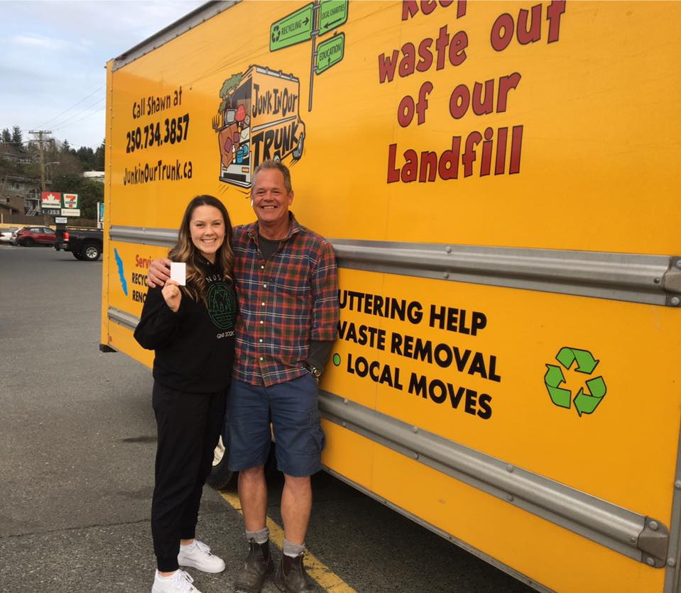 Shawn with a local customer holding a referral card beside the yellow truck