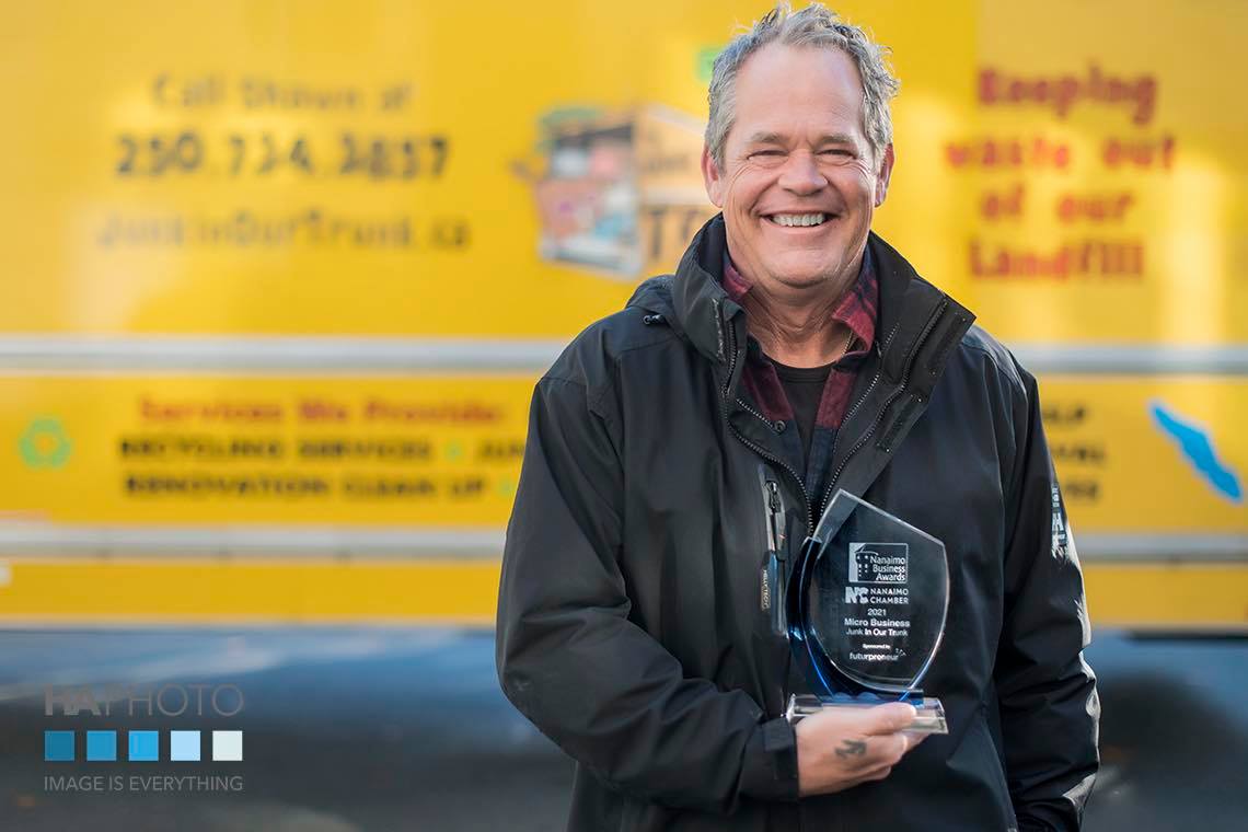 Shawn smiling in front of the Junk In Our Trunk truck holding the 2021 Nanaimo Business Awards Micro Business trophy